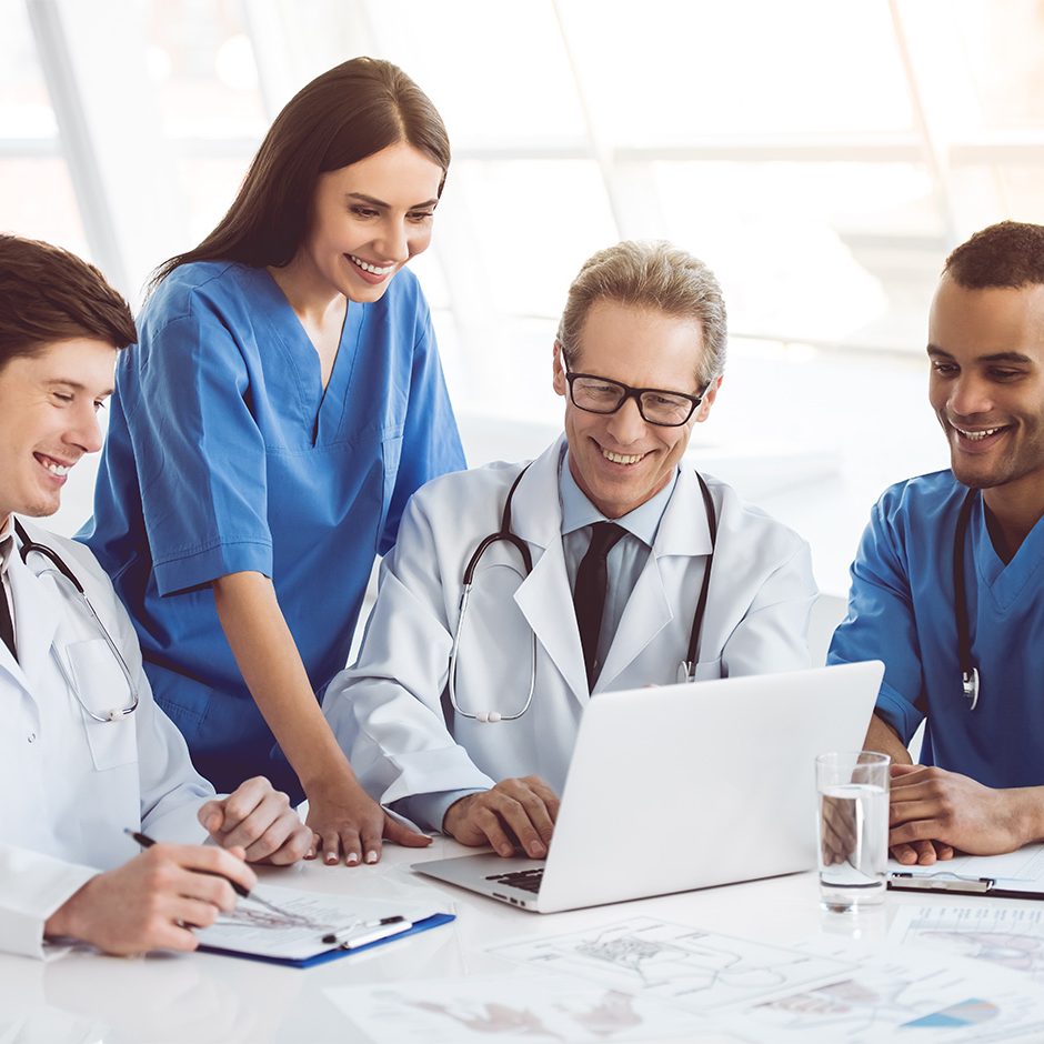 Successful medical doctors are using a laptop and smiling while having a discussion